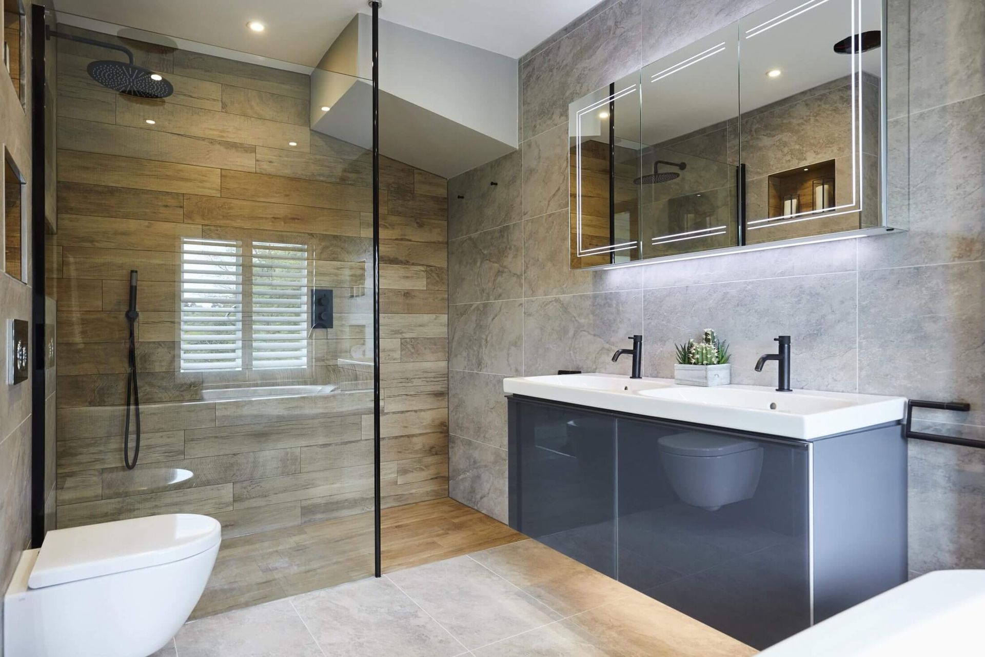 Modern bathroom with a glass shower, floating vanity, and gray tile walls.