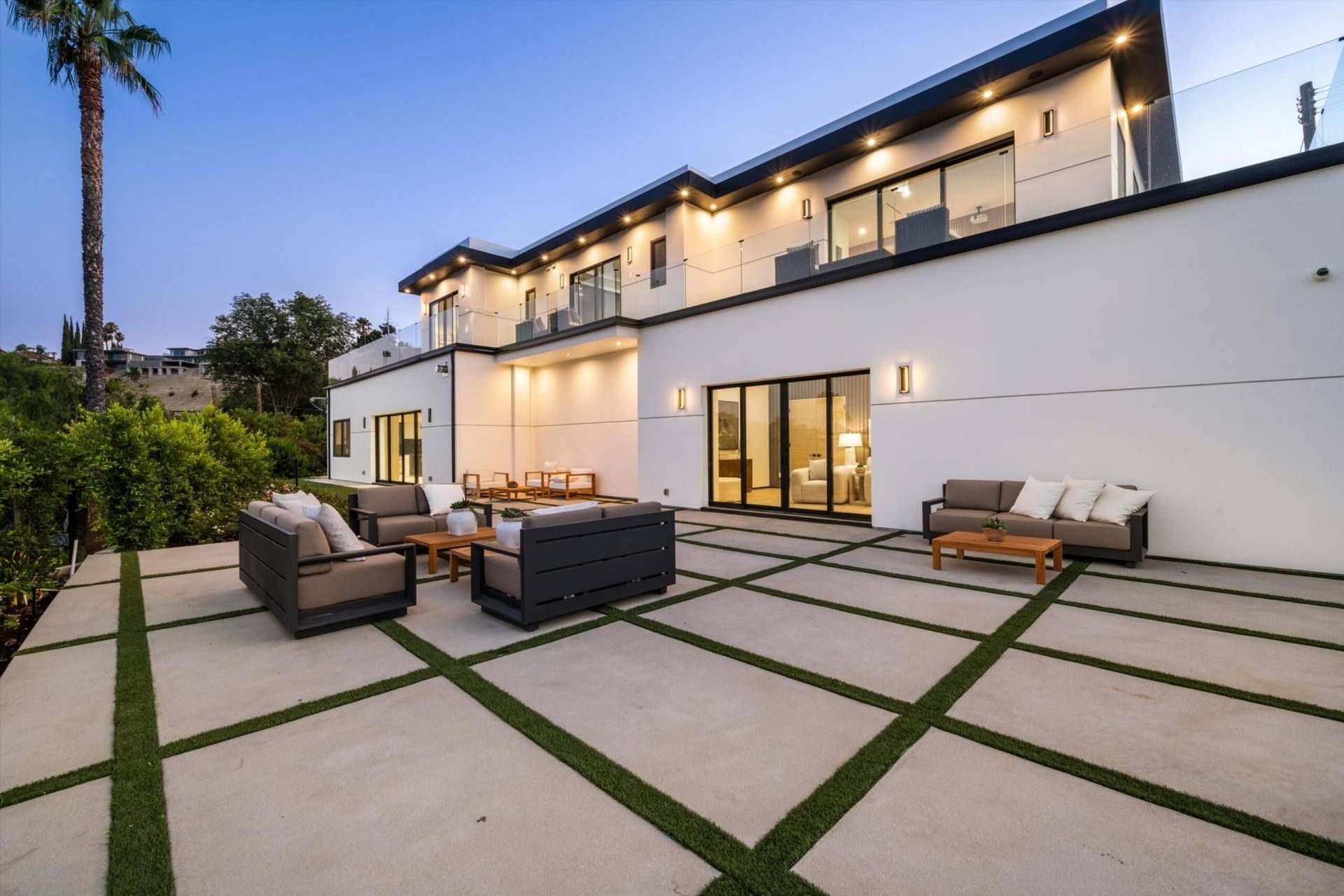 Modern white house with outdoor seating area; patio with grass accents.