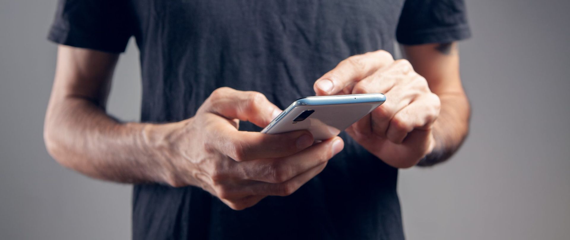 Un hombre sostiene un teléfono celular en sus manos.