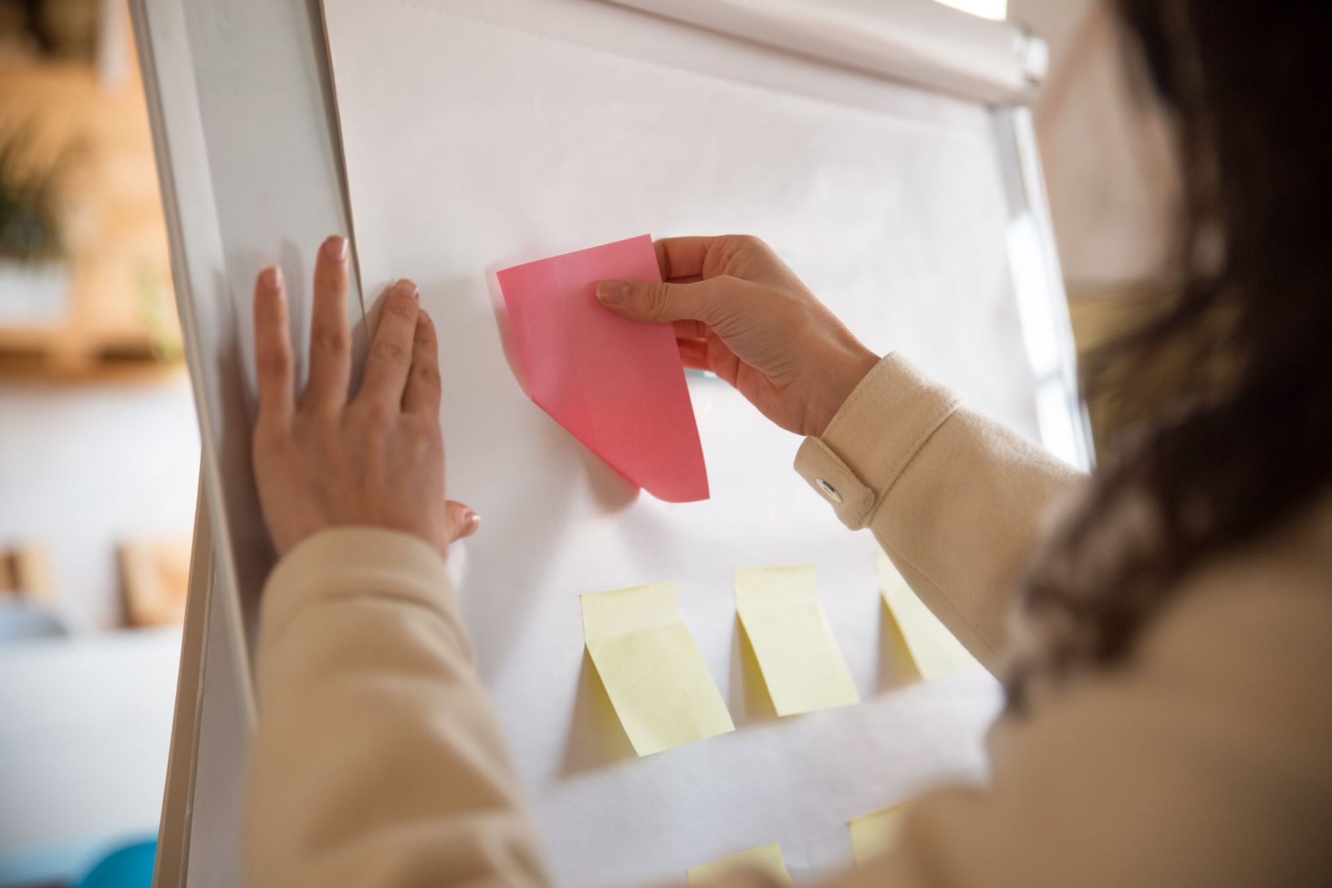 Una mujer está colocando notas adhesivas en una pizarra.