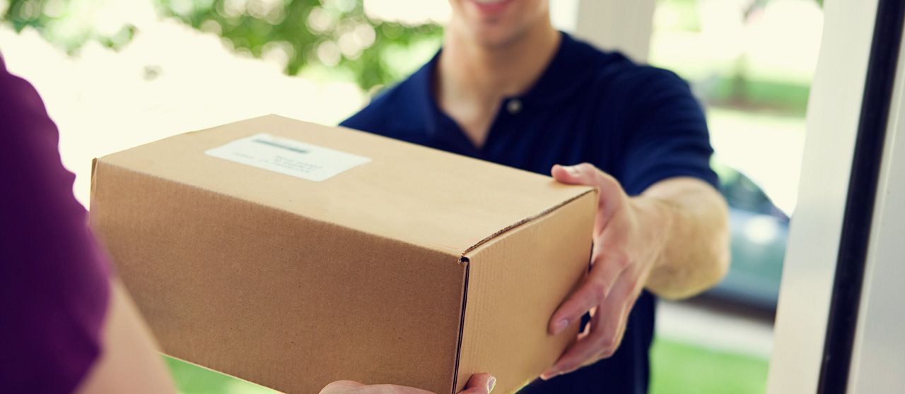 Un repartidor le está entregando una caja a una mujer.