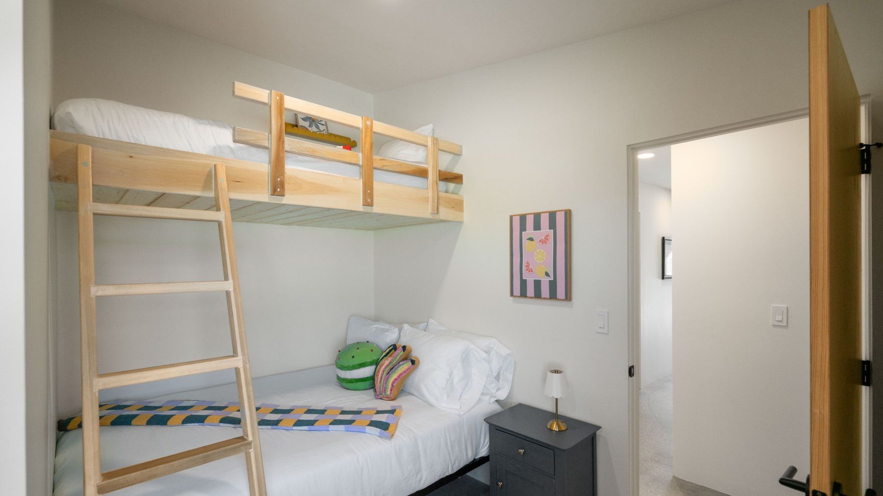 Bright bedroom with white bed, ceiling fan, TV, and sliding glass doors to a balcony.