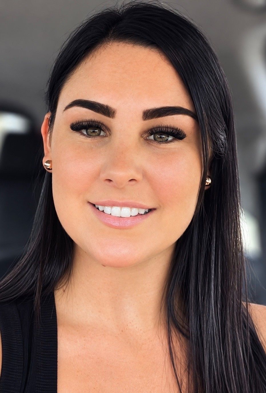 Smiling woman with long dark hair, wearing black, against a soft blurred background — Statix Hair in Rockhampton City, QLD