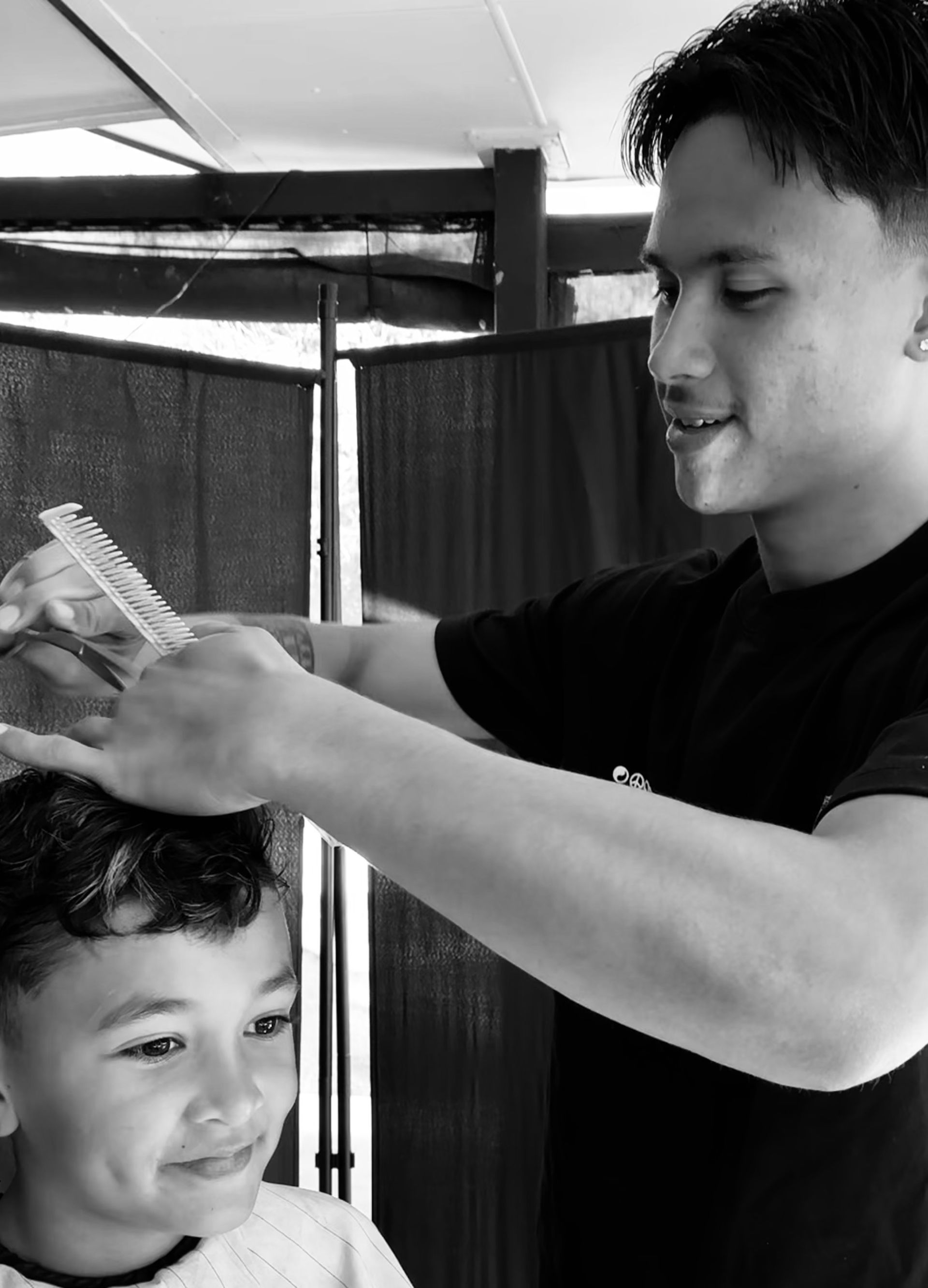 Person Cutting a Child’s Hair Indoors, Both Focused and Smiling