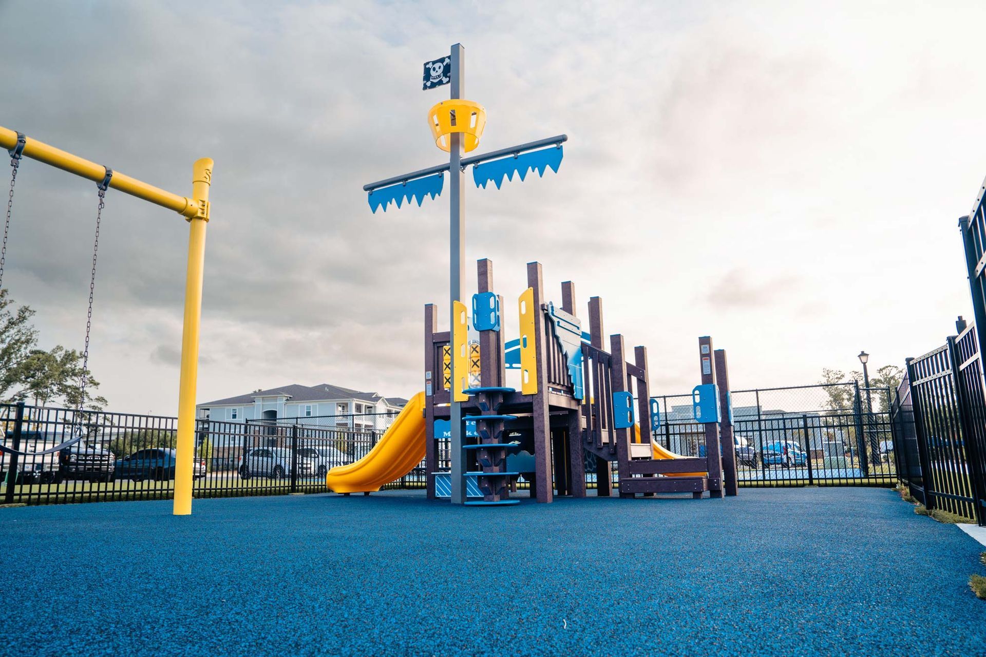 A playground with a pirate ship slide and swings.