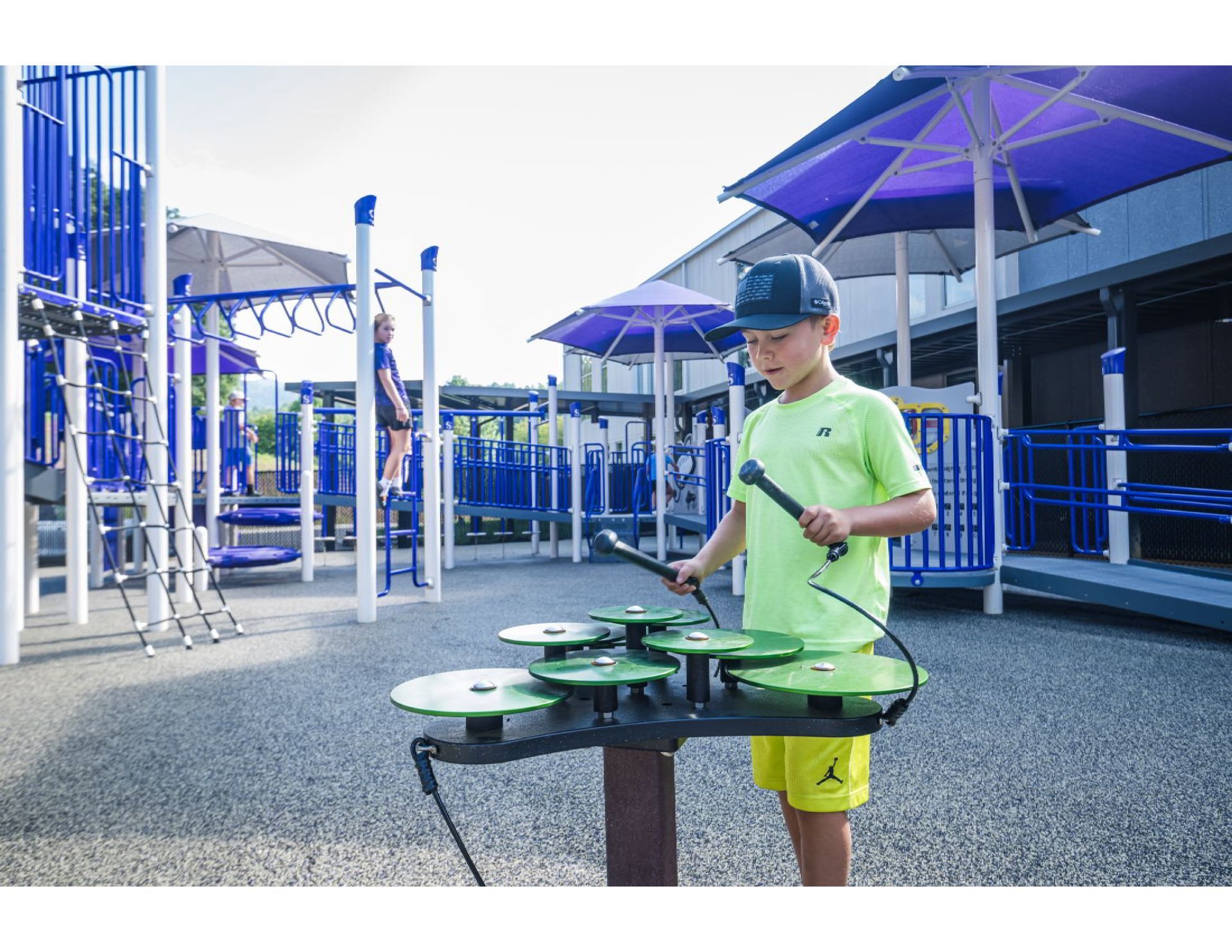 A young boy is playing a musical instrument in a playground.
