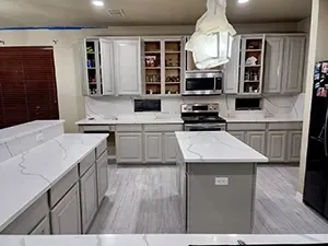 Bright modern kitchen with white cabinets, island, and gray floor tiles