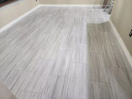 Empty hallway with light gray wood-look flooring and beige walls, viewed from one end.