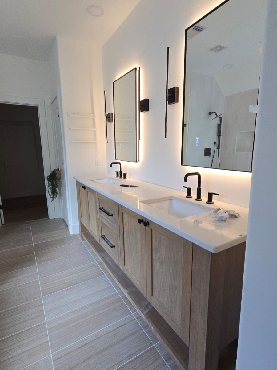 Modern bathroom with double sinks, wood vanity, mirrors, and wall sconces in soft lighting