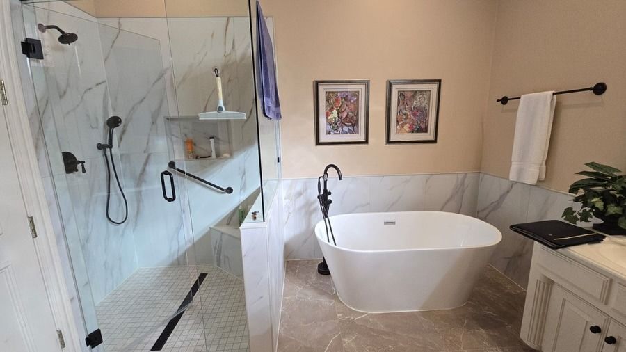 Modern bathroom with walk-in shower, freestanding tub, vanity, and framed wall art.