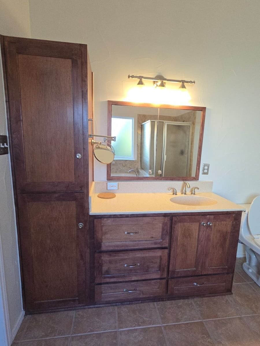 Bathroom vanity with mirror, light, sink, and dark wood cabinets beside a wooden door.