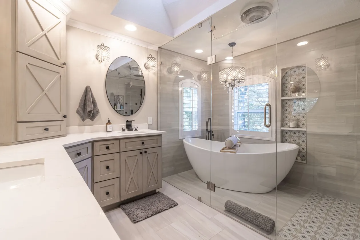 Bright luxury bathroom with freestanding tub, double vanity, large mirror, and tiled shower.