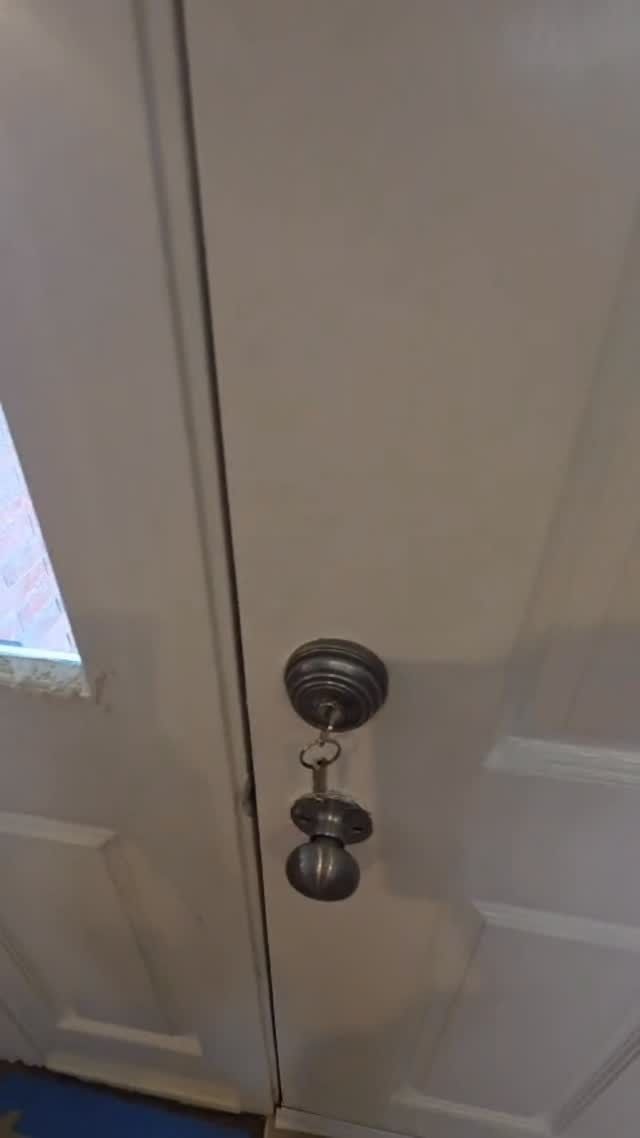 Two white closet doors with a brass knob and deadbolt lock, partially closed.