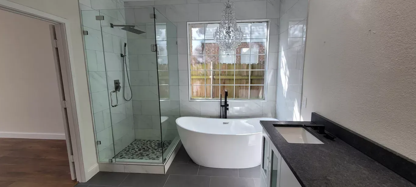Modern bathroom with glass shower, freestanding tub, and dark vanity countertop