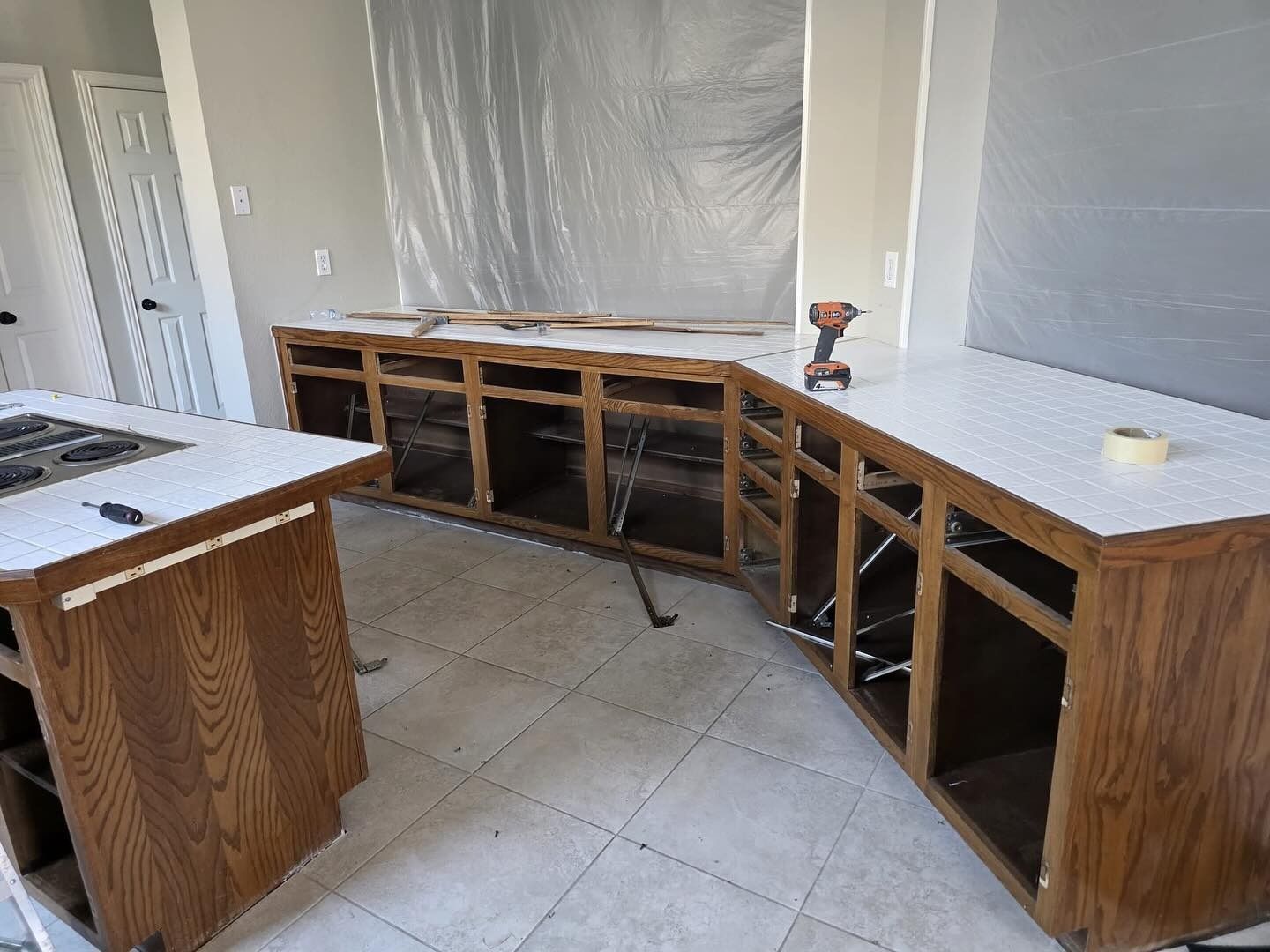 Kitchen under construction with curved wooden lower cabinets and a white countertop on the left
