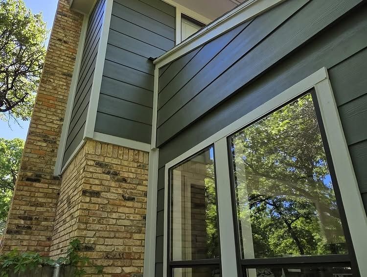 Exterior of a modern house with stone siding, gray paneling, and large reflective windows