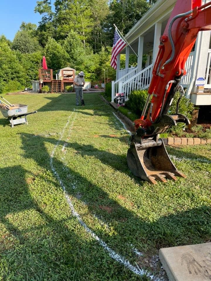Backyard with excavator, worker, lawn markings, and a porch with an American flag.