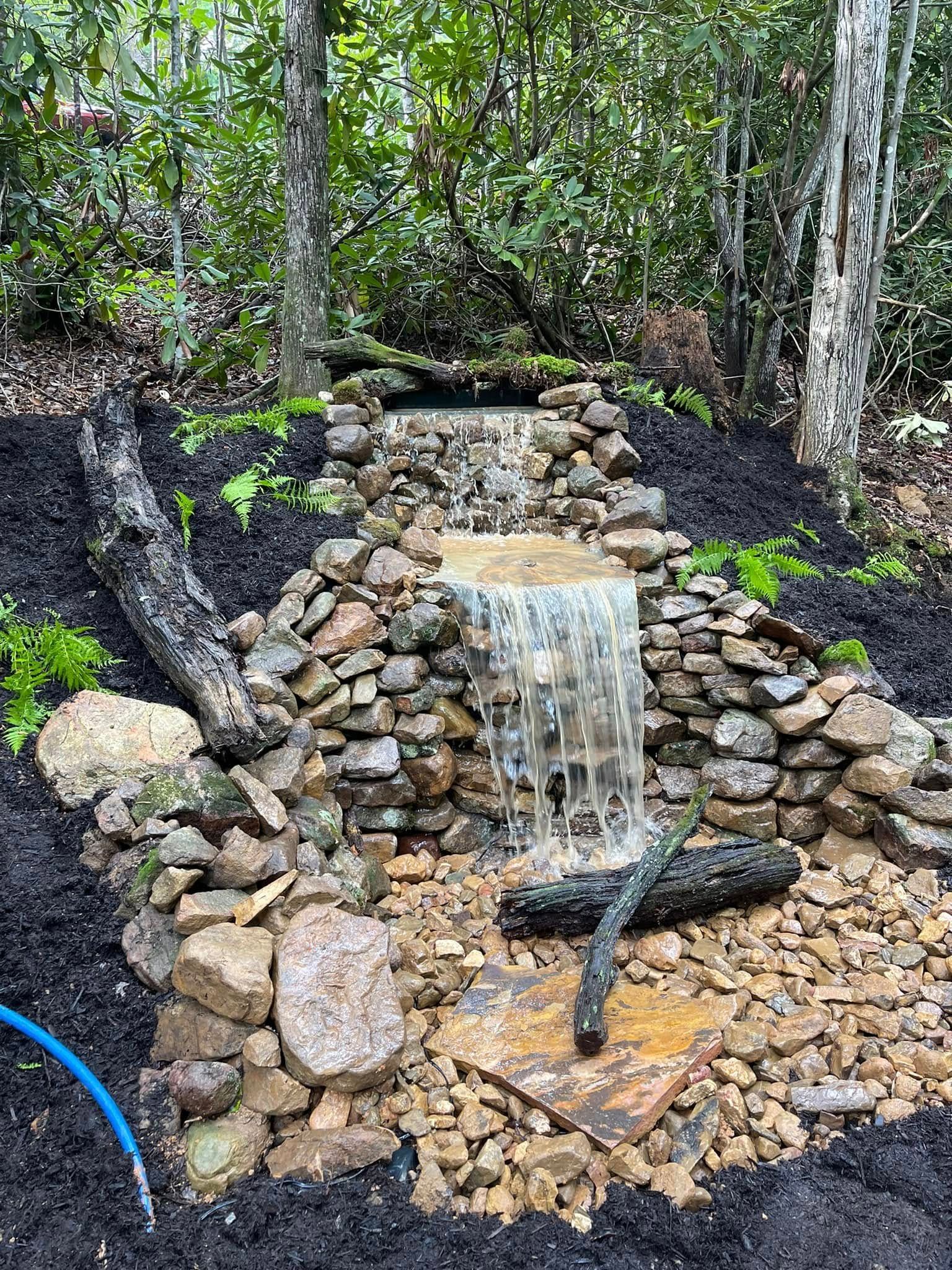 Rock waterfall flowing over stacked stones in a wooded garden