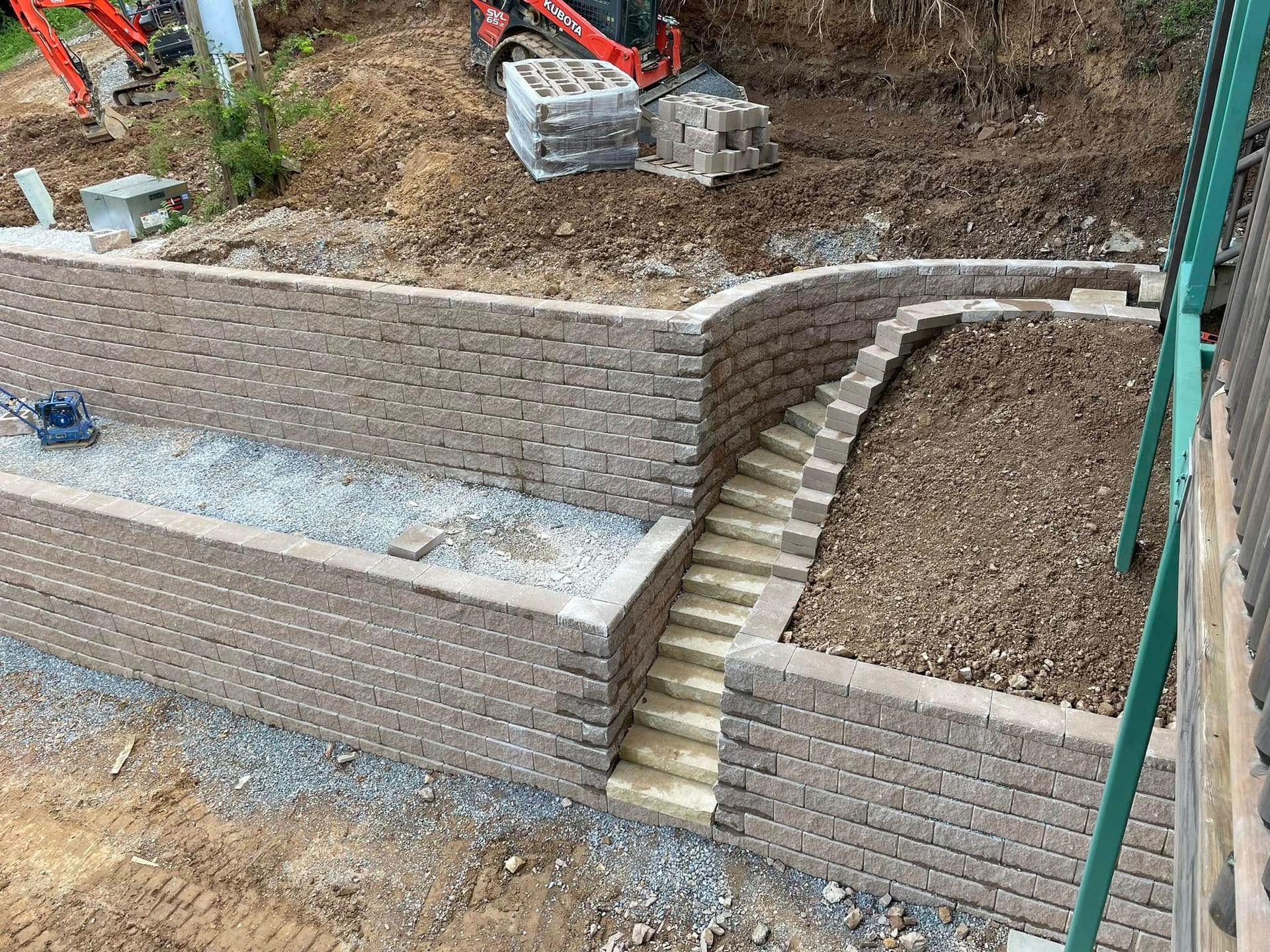 Outdoor terraced retaining walls with stone steps and excavated dirt in a construction site