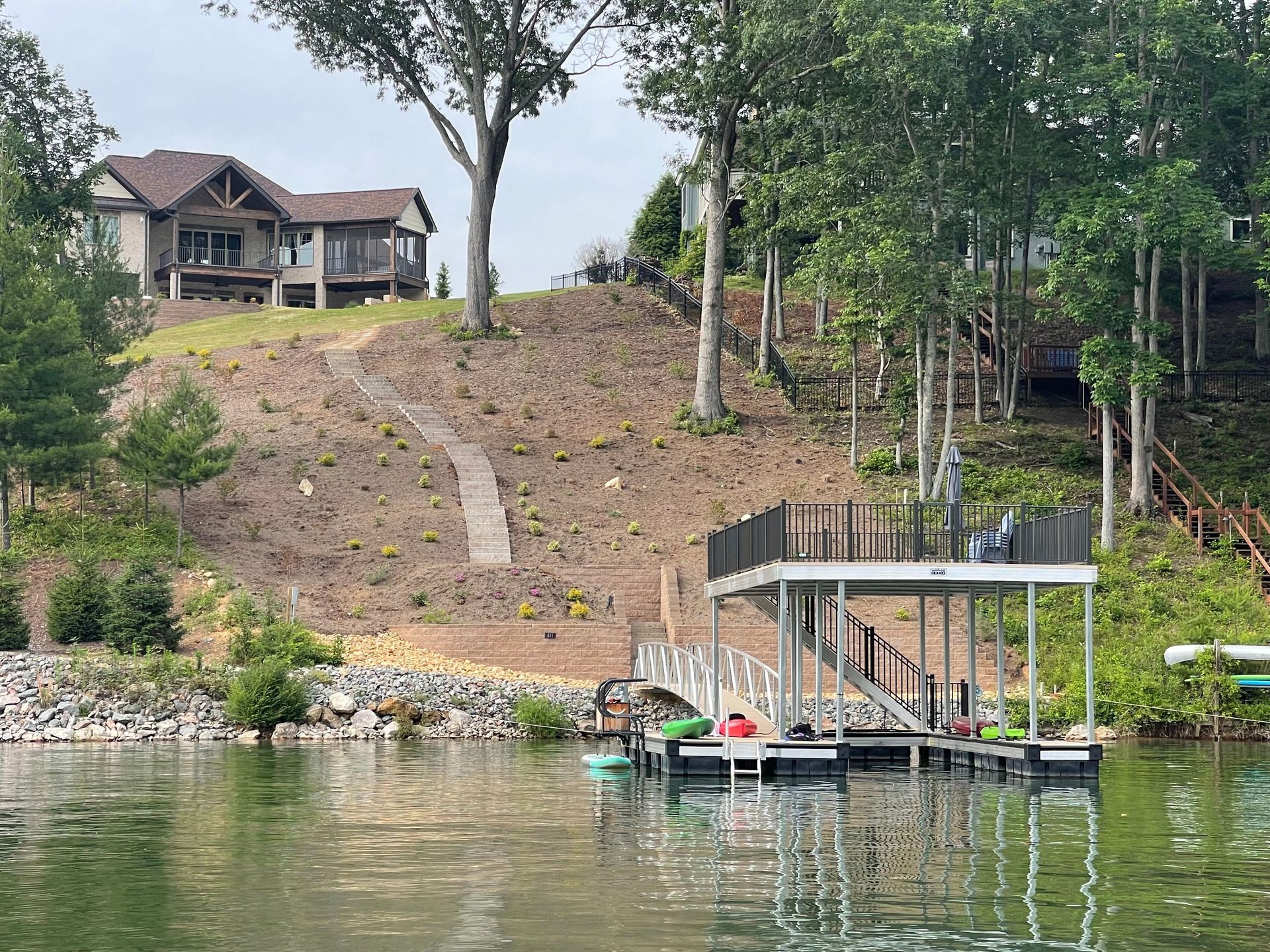 Lakeside hillside with dock, boathouse, and houses among trees