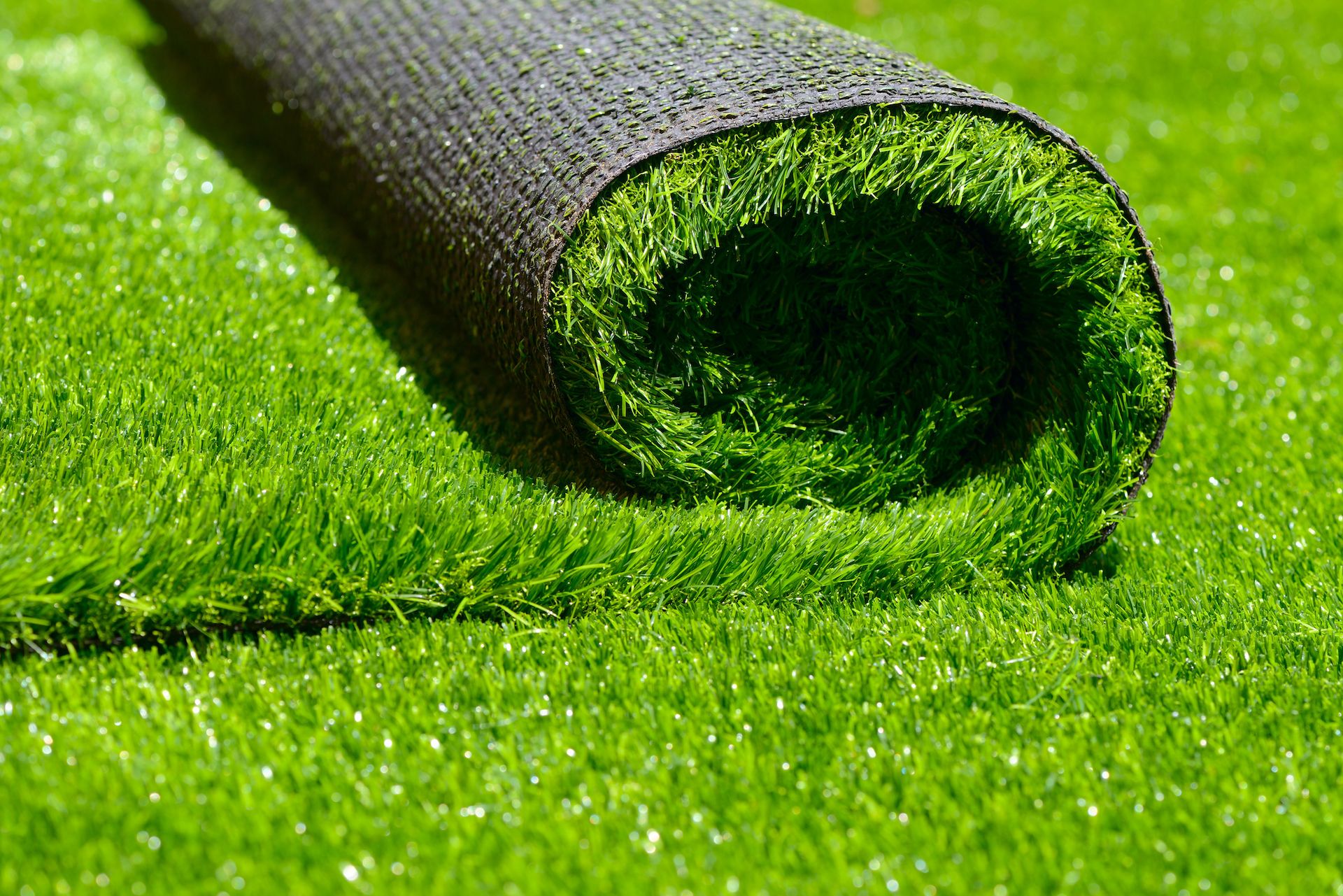 Rolled artificial turf on bright green grass