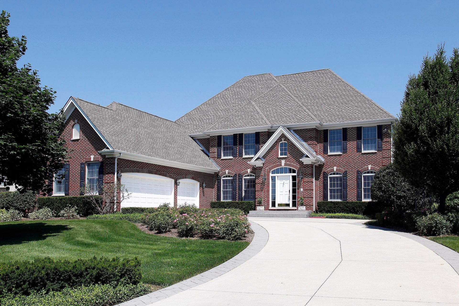 Brick house side yard with exposed dirt and a window beside a paved driveway