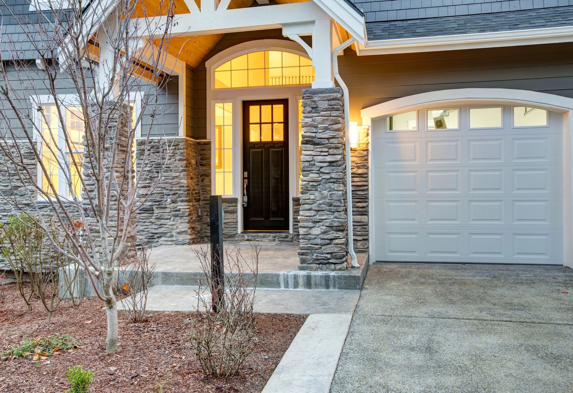 Paver patio with black metal fence gates and a beige house wall on the right
