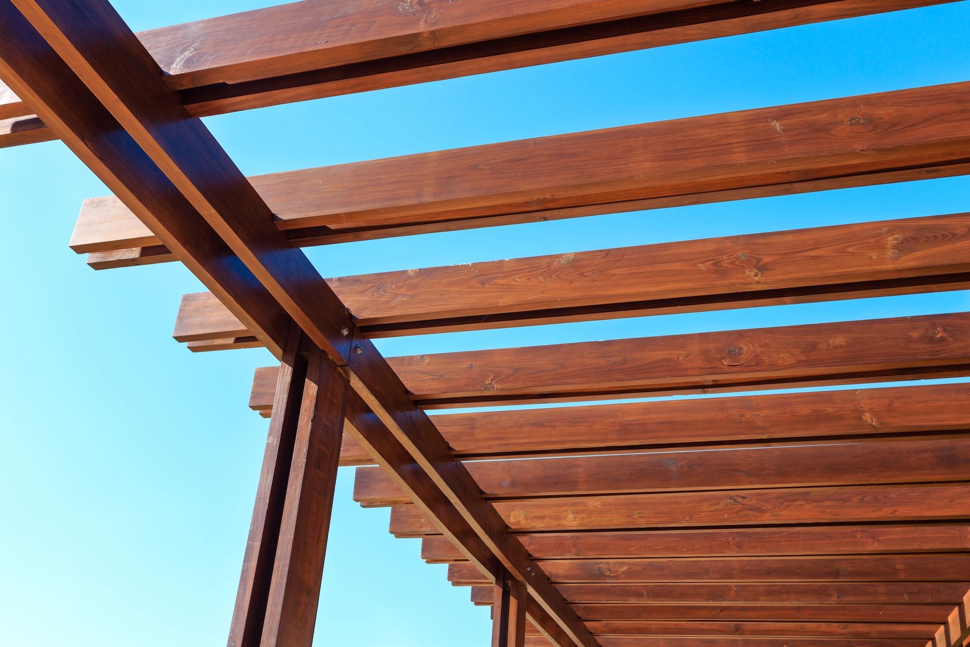 Wooden pergola beams against a clear blue sky