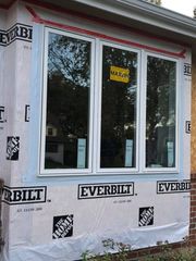 Window framed in house wrap with EverBilt branding and a yellow sticker in the center window