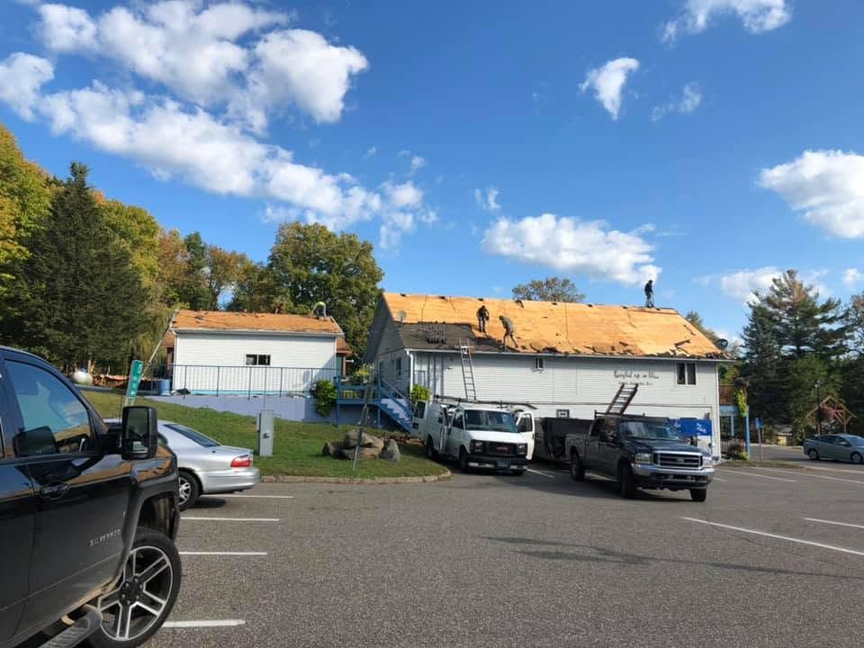 Parking lot with two white utility trucks in front of a building under a blue sky