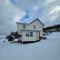 White house in a snowy field under a cloudy sky.