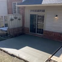 Newly poured concrete patio outside a house with a sliding glass door.