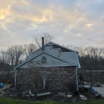 Brick building with a blue roof and a chimney against a cloudy sky.