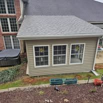 A sunroom addition with three windows and a hot tub in the yard.