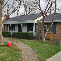 Gray-roofed house with brick details and a winding stone path leading to the front door.