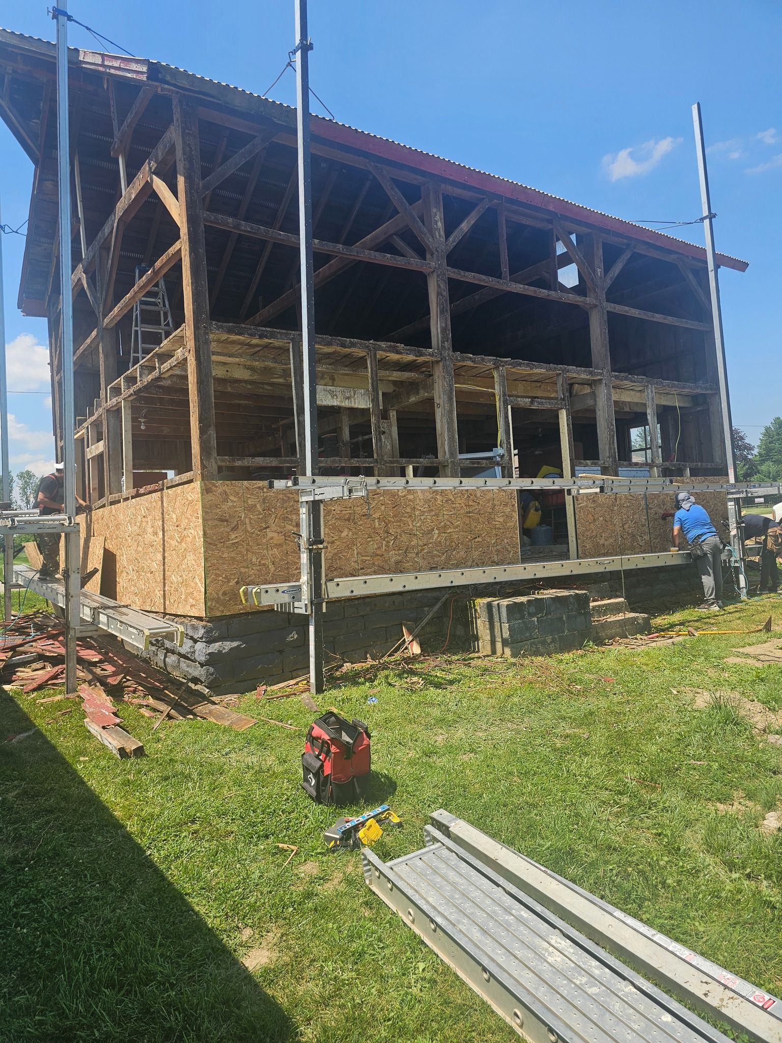 Building undergoing renovation. Exposed wooden structure, partially covered, scaffold in place.