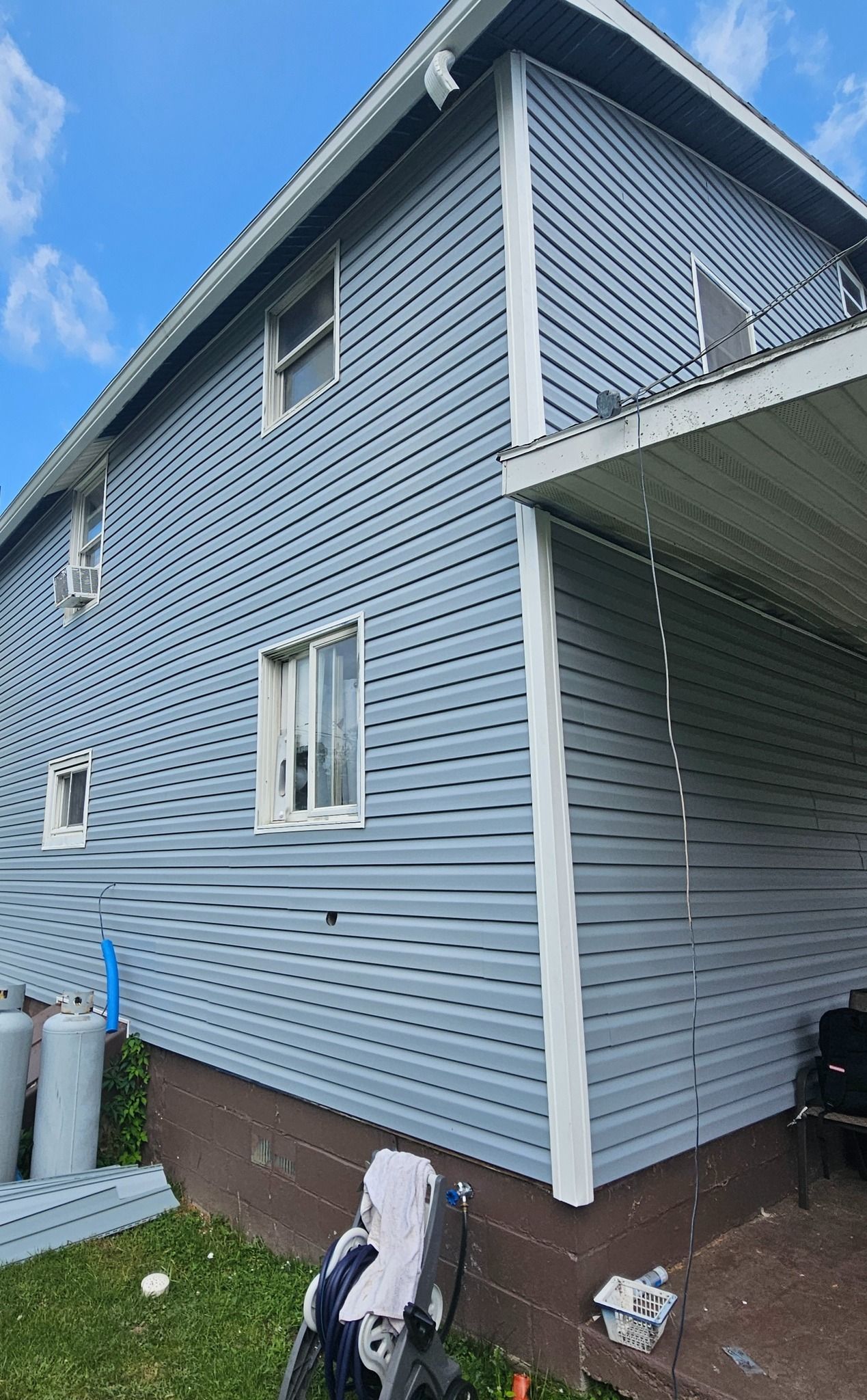 Blue house with white trim, covered porch, two windows, swirls painted on siding.