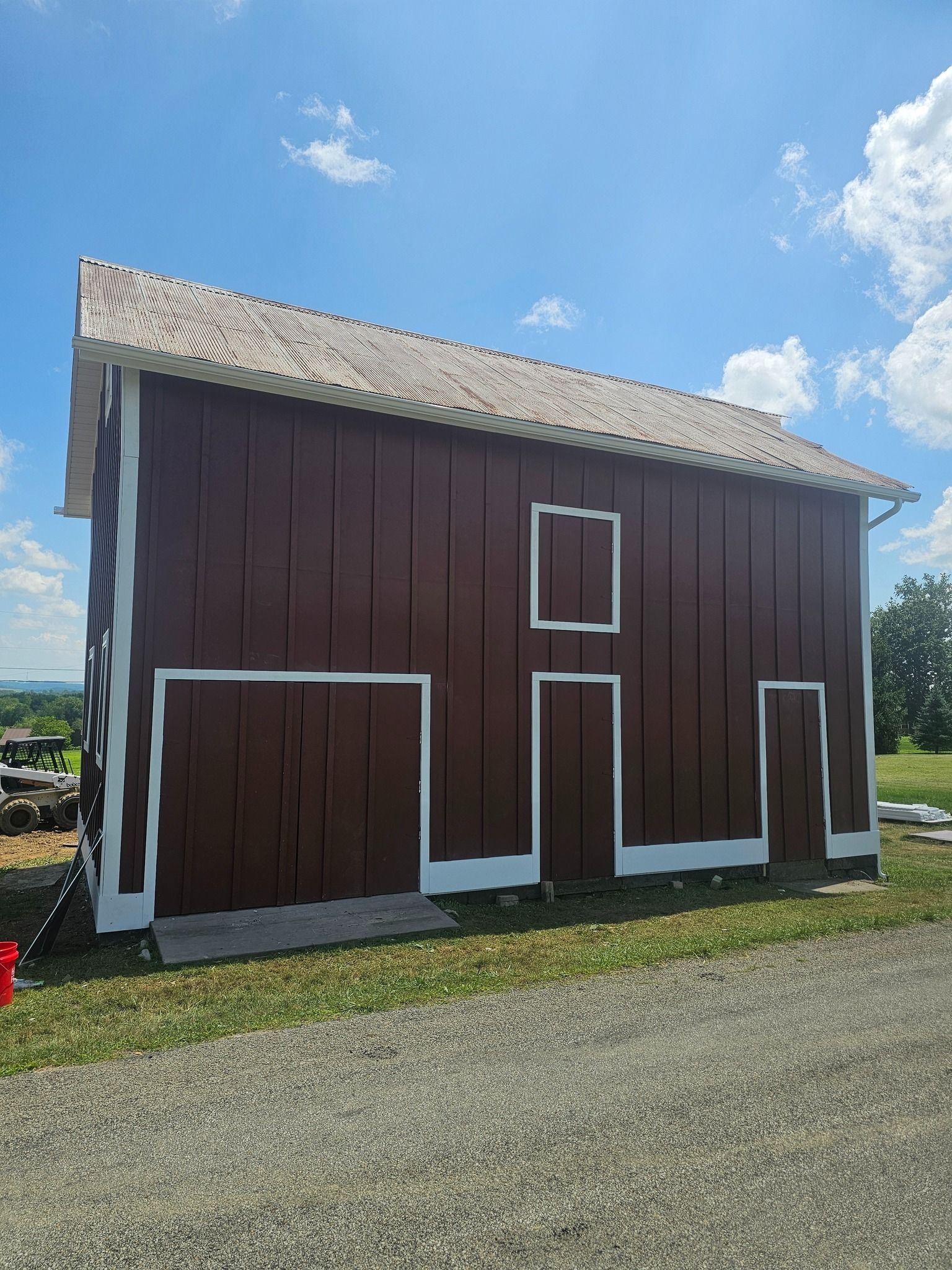 Red barn with white trim under a blue sky.