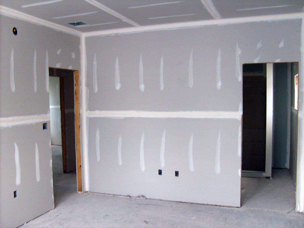 Unfinished room with drywall, white and gray walls, doorway openings, and visible outlet holes