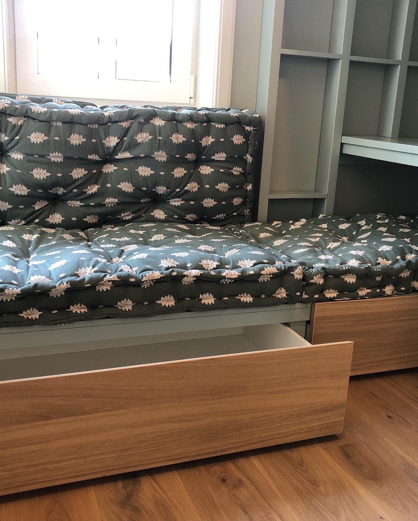 Ingebouwde slaapbank met lades. Gevoerd matras en rugleuning, houten frame en gedeeltelijk open lade.