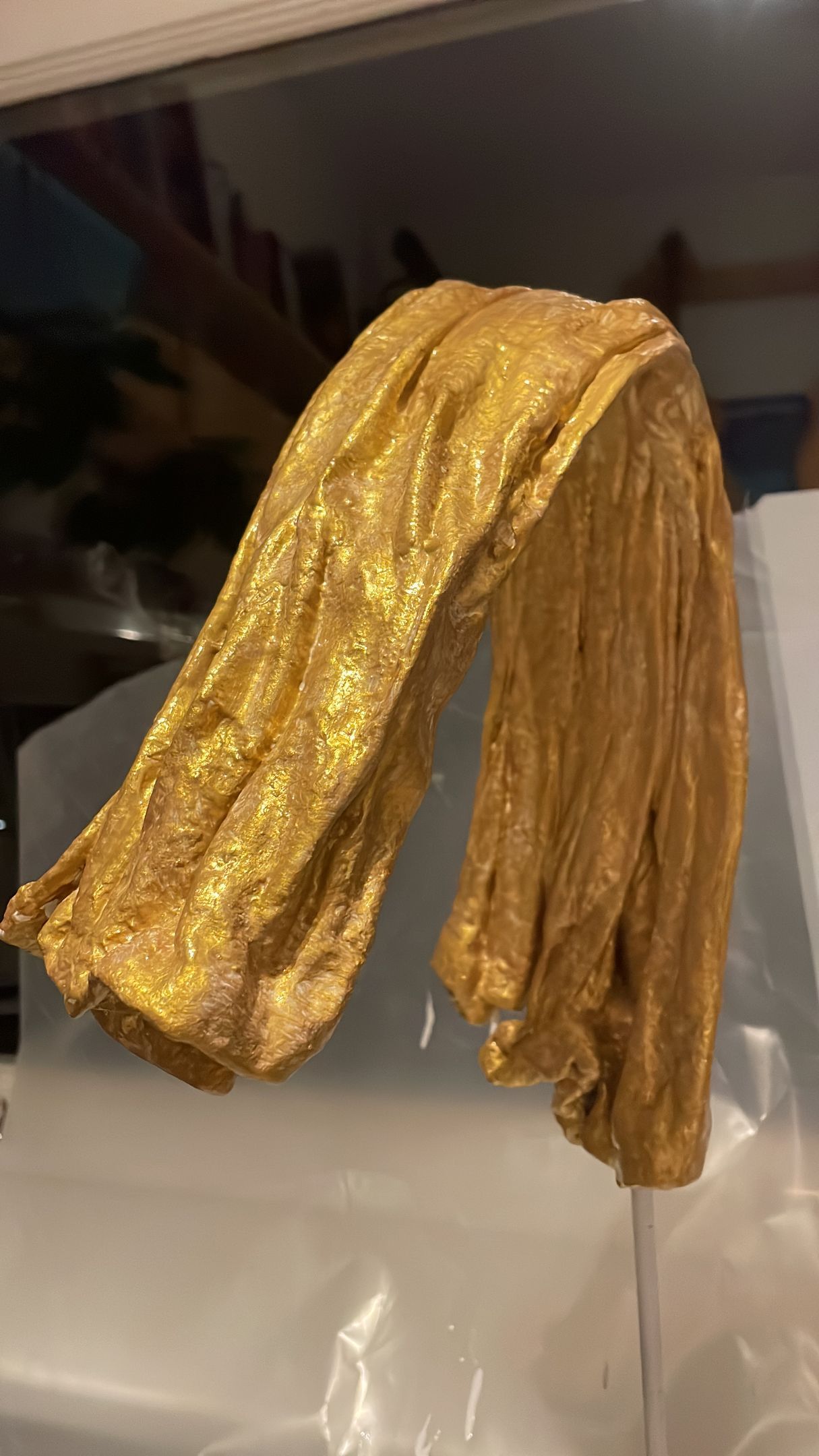 Gouden, glinsterende stof, gedrapeerd tegen een transparante ondergrond.