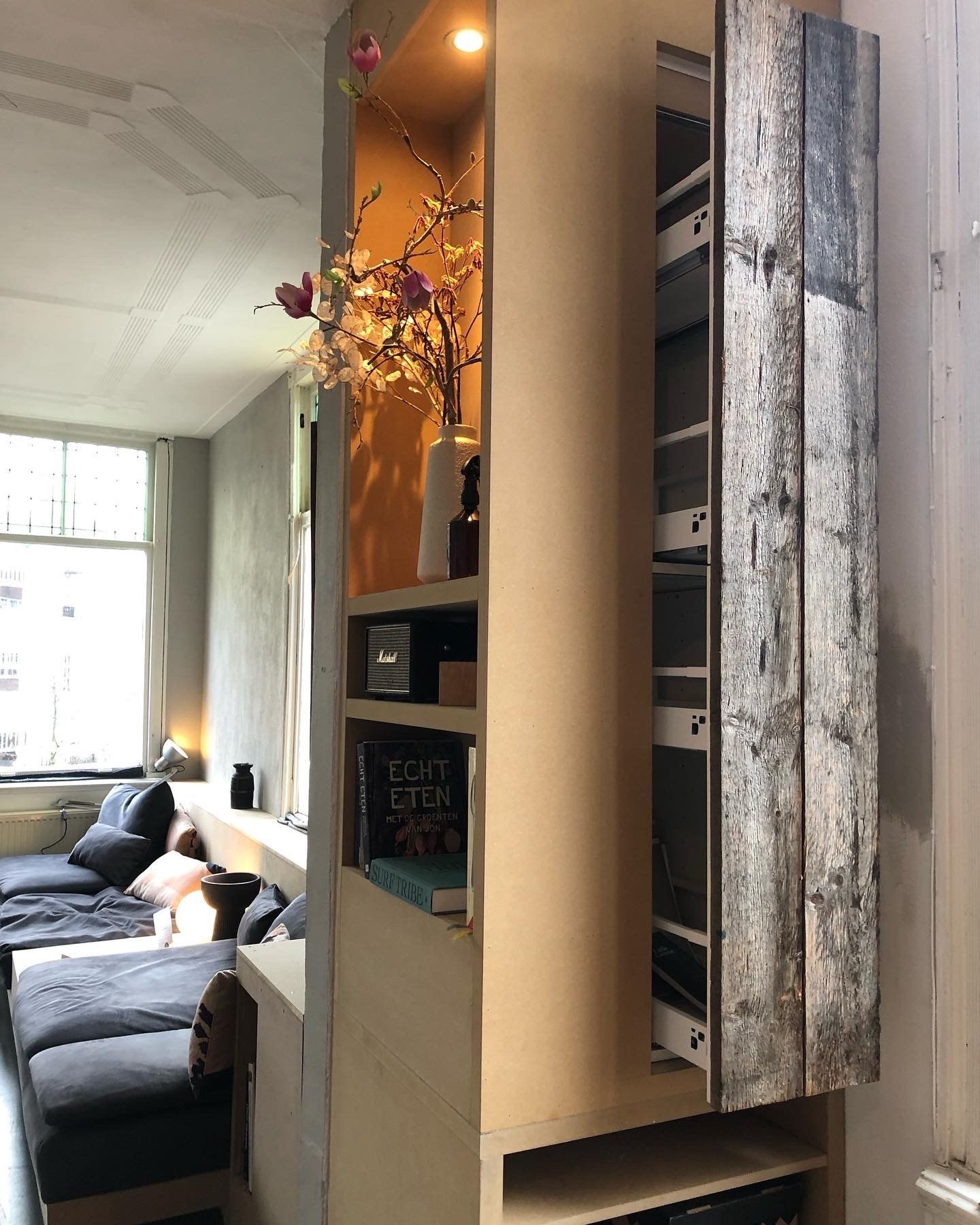 Ingebouwde kast met schuifdeuren, planken en een buitenkant bekleed met houten panelen. 