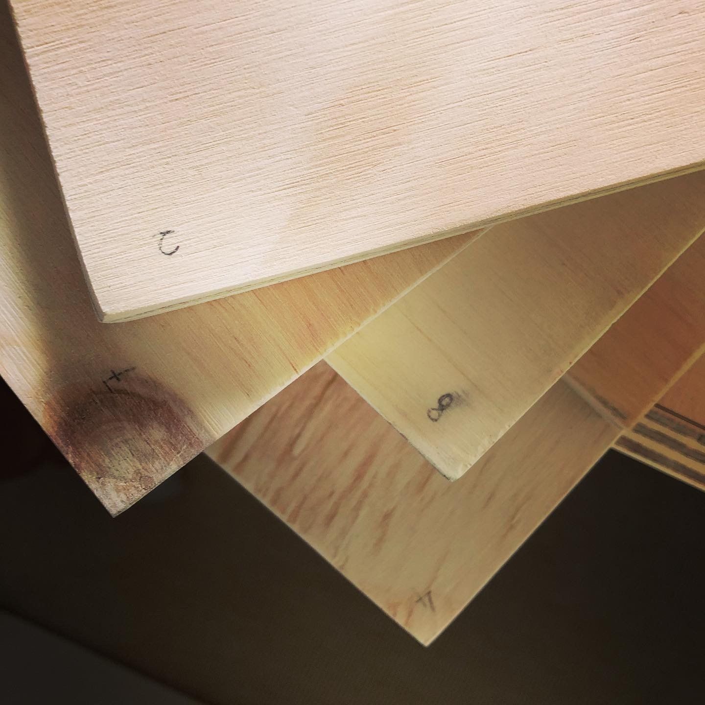 Detailopname van een stapel stalen van houten multiplex, in verschillende tinten lichtbruin.