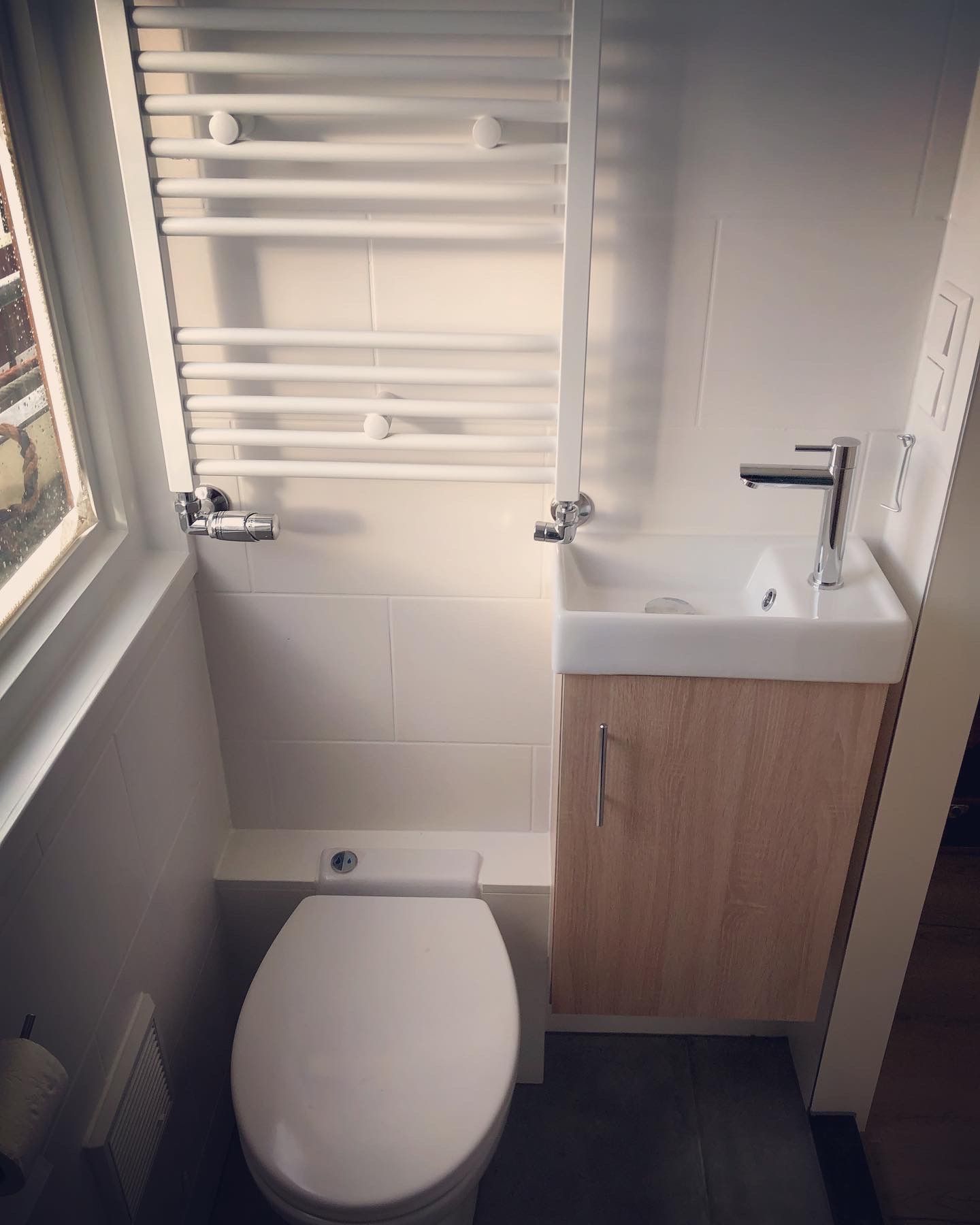 Kleine, moderne badkamer met toilet, wastafel en handdoekrek.