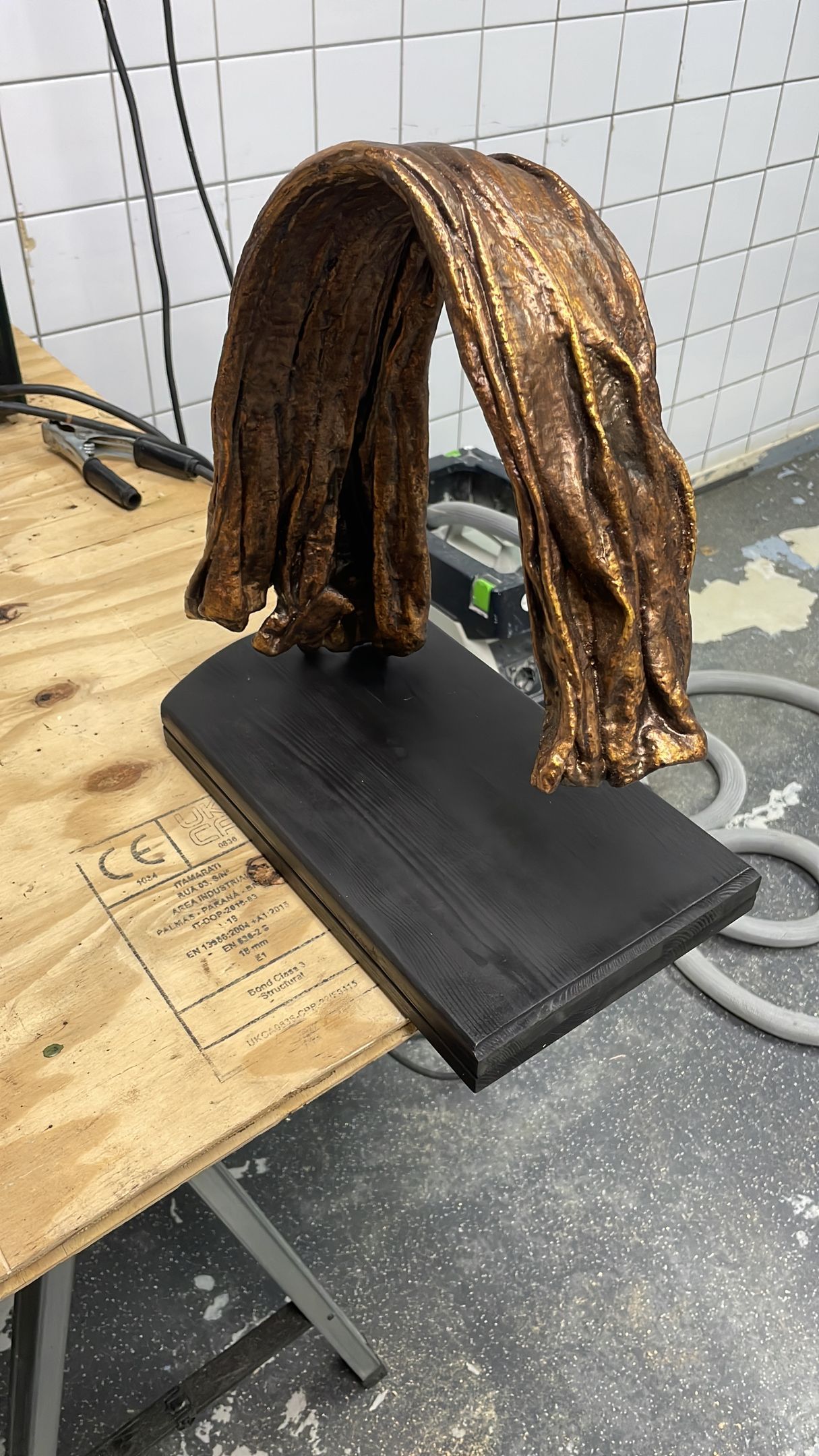 Gebeeldhouwd bruin haar op een zwarte rechthoekige basis, op een houten ondergrond.