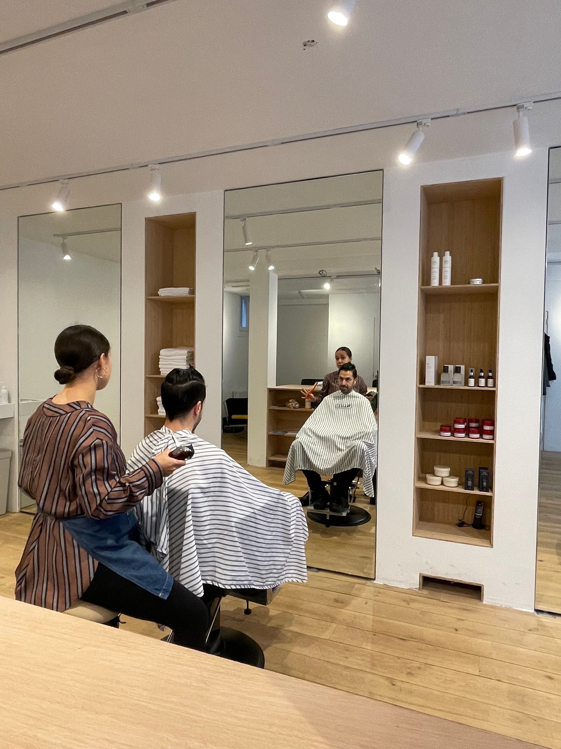 Een kapper knipt het haar van een klant in een salon. 