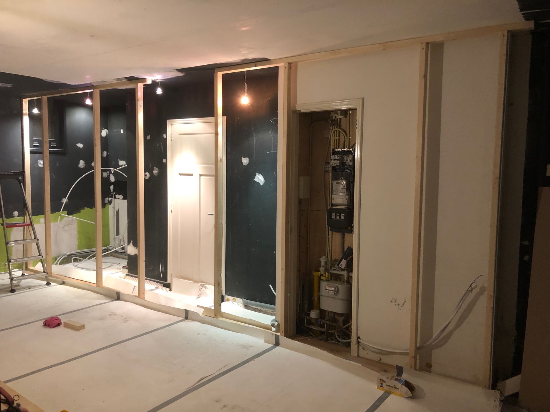 Binnenruimte in aanbouw, met houten frame, elektrische bedrading en een zichtbare deur.