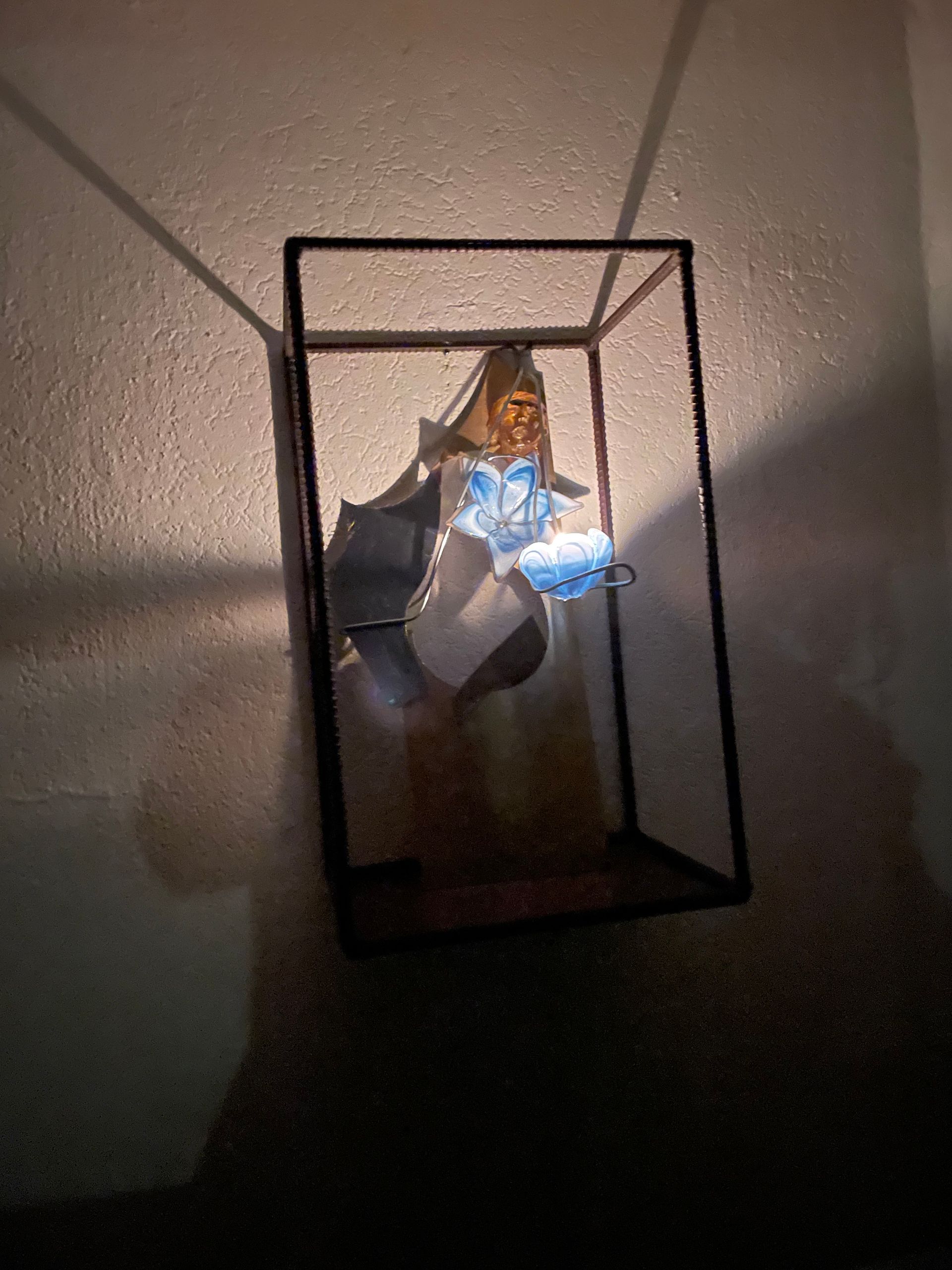 kunstwerk in een zwarte, rechthoekige doos. Het kunstwerk lijkt een mixed-media werk te zijn met blauwe en gouden elementen.