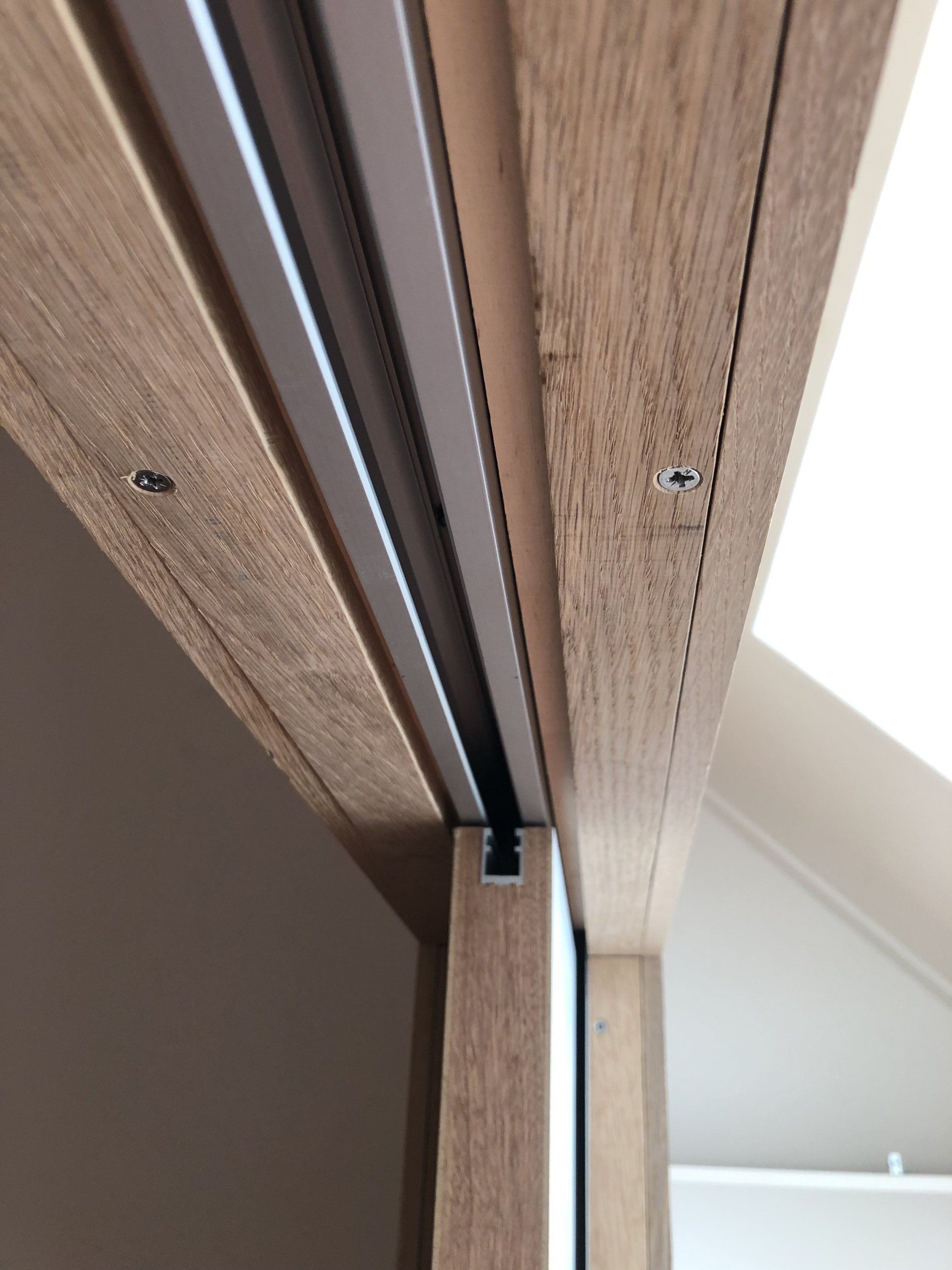 Houten deurkozijn met rails voor een schuifdeur; bruine en lichte neutrale tinten.