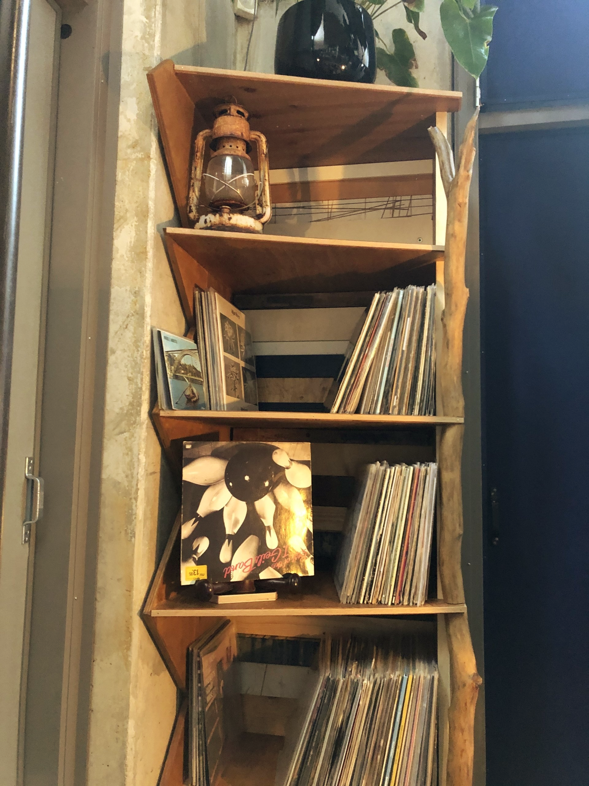 Houten plank met platen, een lantaarn en decoraties tegen een betonnen muur.